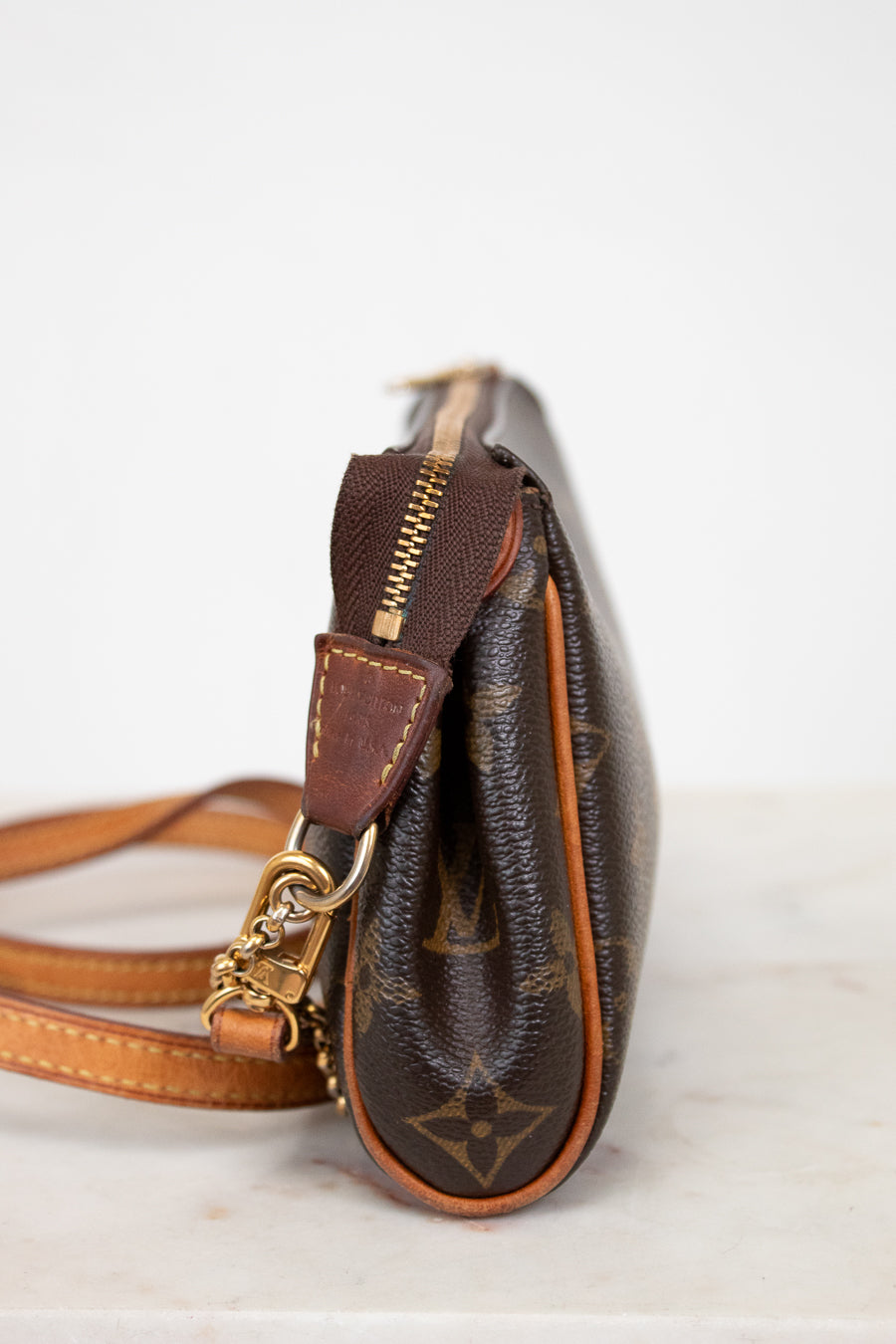 Brown leather handbag with gold accents on a light background