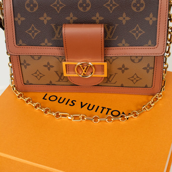 Louis Vuitton monogram shoulder bag in brown coated canvas with tan leather trim and a gold-tone chain strap, displayed on top of an orange Louis Vuitton box.