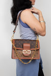 A woman wearing a light blue top and skirt carries a Louis Vuitton monogram shoulder bag with a brown leather flap, gold-tone hardware, and a gold chain strap against a plain light gray background.