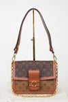 A Louis Vuitton monogram shoulder bag in brown coated canvas with tan leather trim and gold-tone hardware, displayed on a stand against a white background.