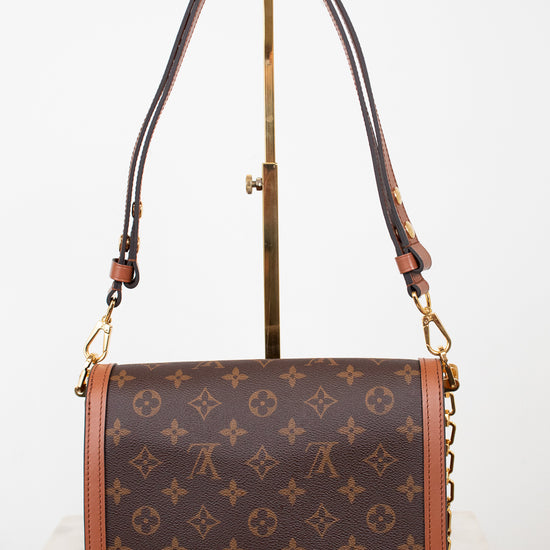 Louis Vuitton monogram canvas shoulder bag with brown leather trim and gold-tone hardware, displayed on a stand against a white background.
