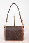 Louis Vuitton monogram canvas shoulder bag with brown leather trim and gold-tone hardware, displayed on a stand against a white background.