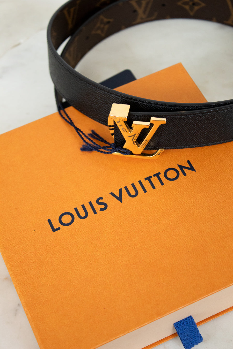 Louis Vuitton belt with gold buckle on an orange Louis Vuitton box
