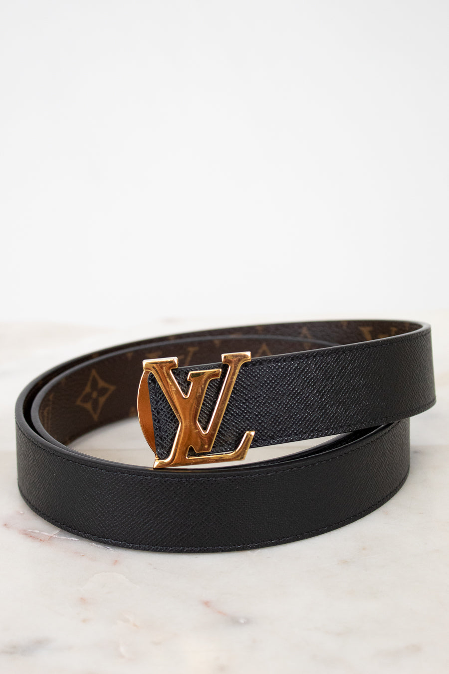 Black belt with gold buckle on a marble surface