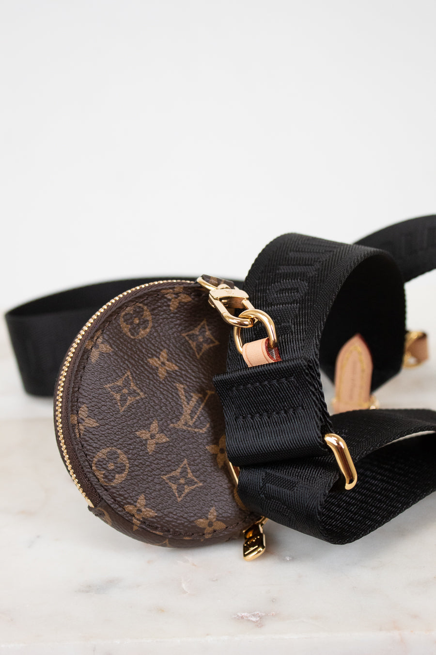 Louis Vuitton monogram bag with black strap on a light background