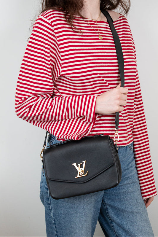 Person wearing a red and white striped shirt with a black Louis Vuitton bag.