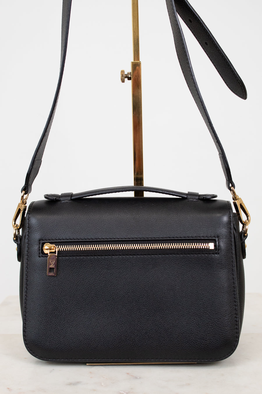 Black leather handbag with gold zipper on a white background