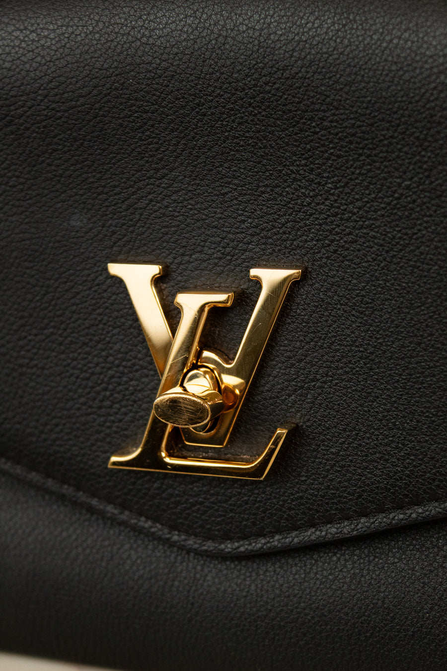 Close-up of a black leather handbag with a gold logo.
