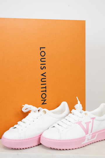 White and pink sneakers with Louis Vuitton logo in front of an orange Louis Vuitton box.