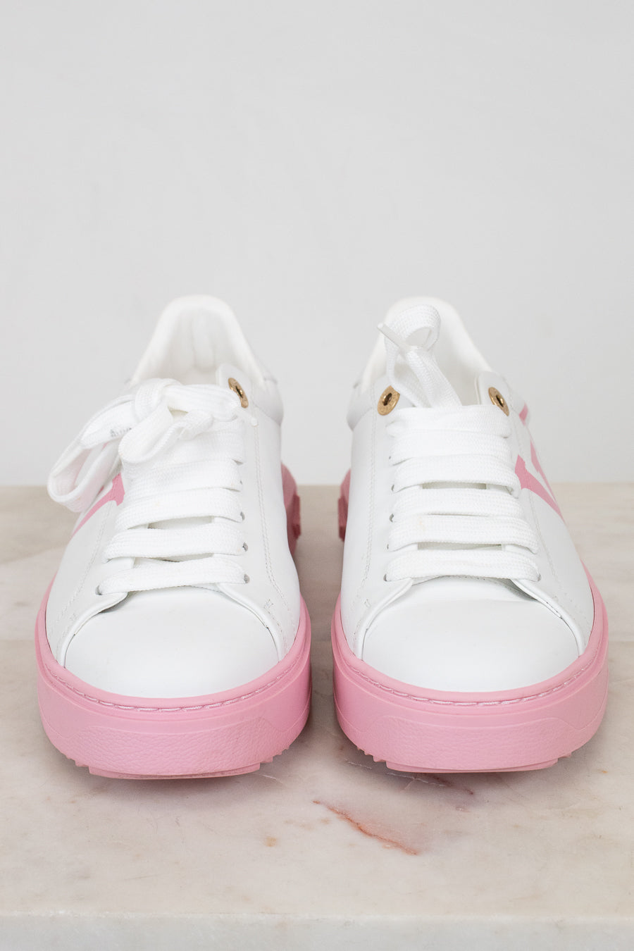 White sneakers with pink soles on a light gray background