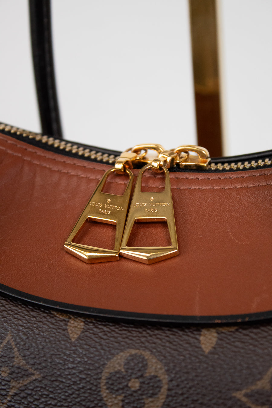 Brown leather handbag with gold hardware on a white background