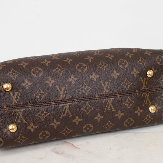 Brown leather handbag with gold studs on a marble surface