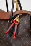Louis Vuitton monogram handbag with a decorative zippers featuring red and black ribbons.