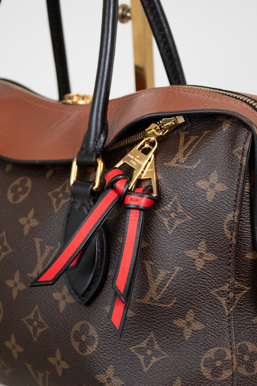 Louis Vuitton monogram handbag with a decorative zippers featuring red and black ribbons.