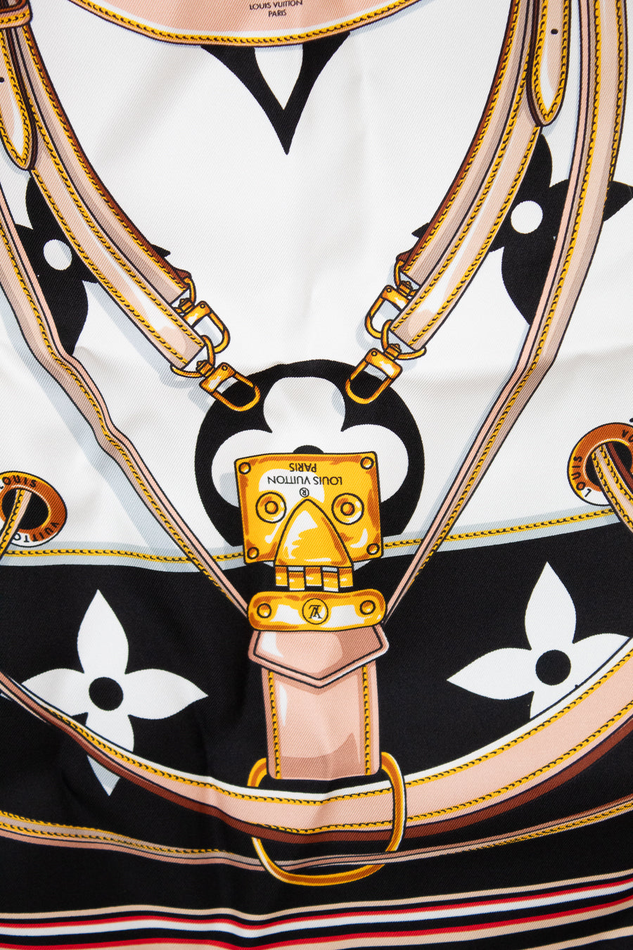 Close up of Louis Vuitton scarf showing detail print that looks like purse straps and purse hardware closure