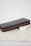 Maroon patent leather wallet with gold zipper on a marble surface