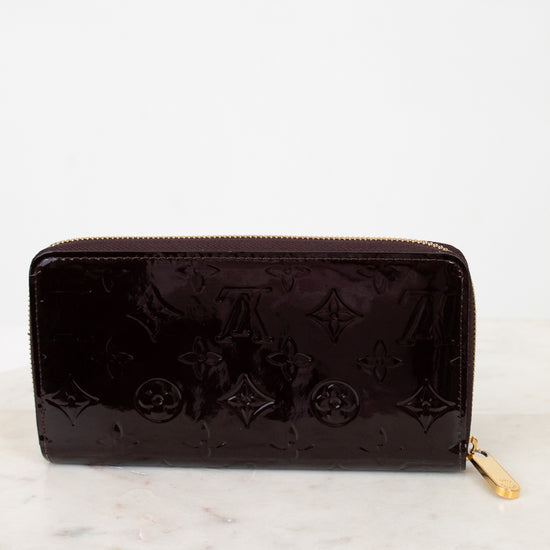 Maroon wallet with monogram pattern on a white marble surface