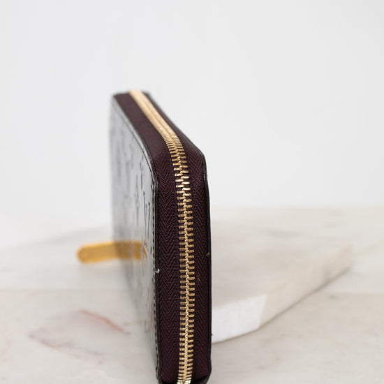 Maroon wallet with gold zipper on a marble surface