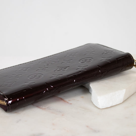 Maroon patent leather wallet on a marble surface