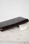 Maroon patent leather wallet on a marble surface