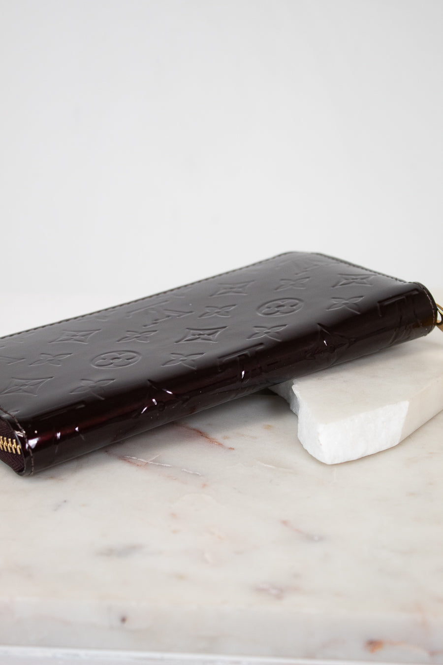 Maroon patent leather wallet on a marble surface