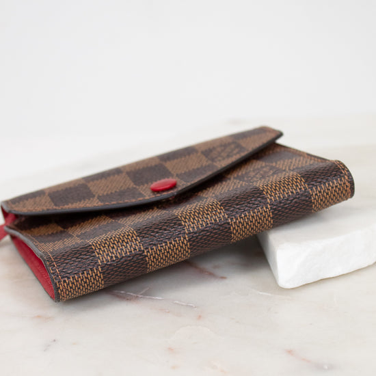 Brown checkered wallet with red accents on a marble surface