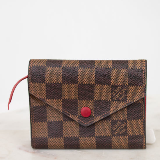 Designer wallet with checkered pattern and red accent on a white background