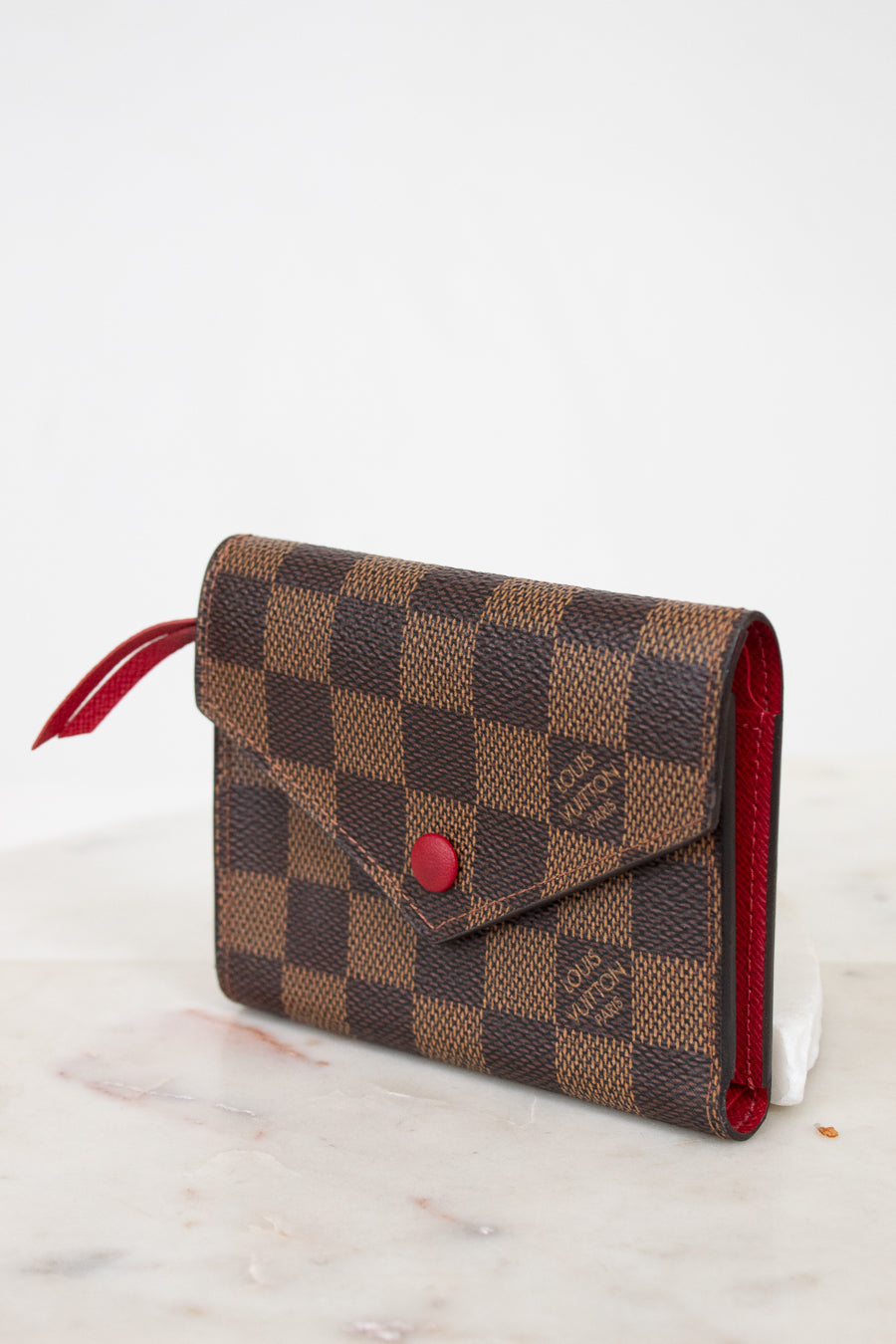 Louis Vuitton wallet with checkered pattern on a white surface