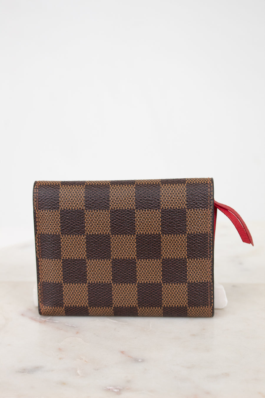 Back of checkered wallet with a red pull on a light background