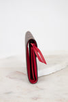 Red side profile of wallet with a red interior on a white marble surface