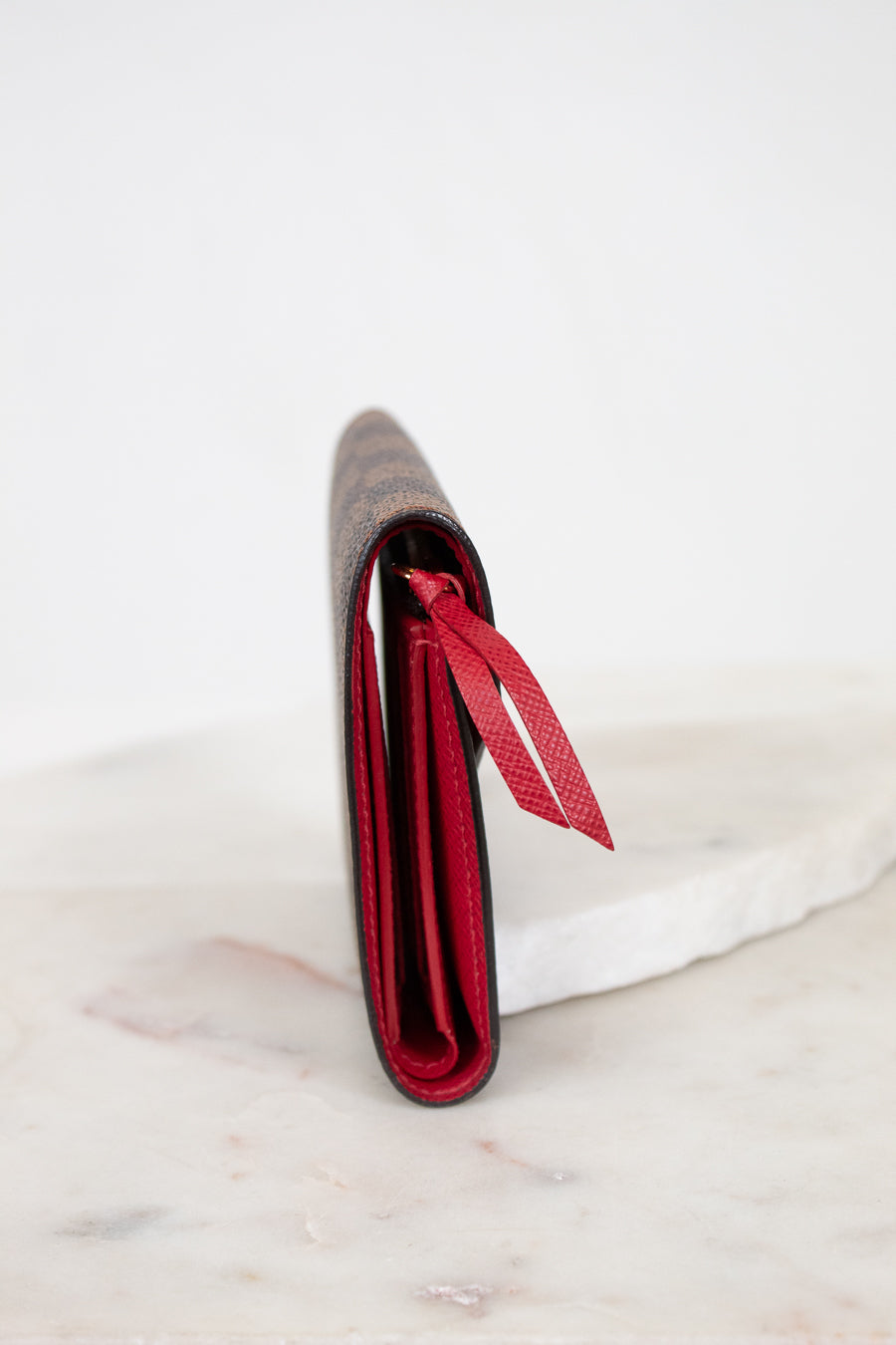 Red side profile of wallet with a red interior on a white marble surface