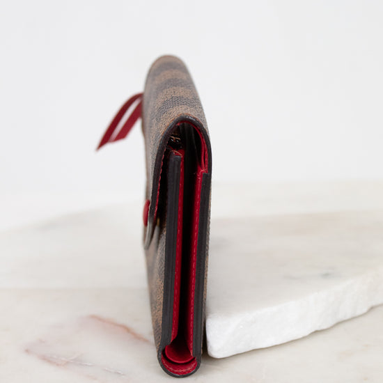 Close-up side profile of a wallet with red interior on a marble surface