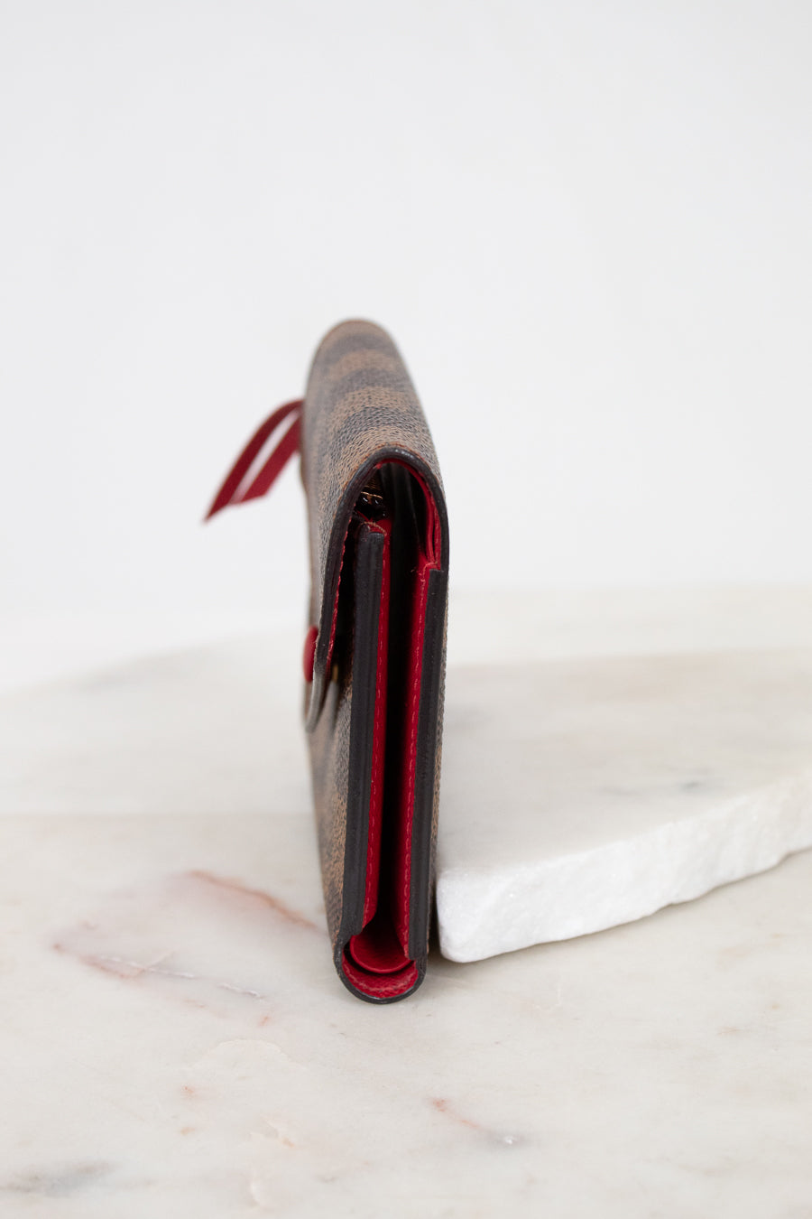 Close-up side profile of a wallet with red interior on a marble surface