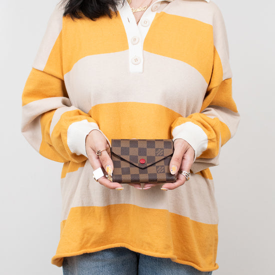 Person wearing a striped shirt holding a small wallet against a plain background