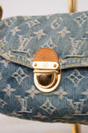 Close-up of a Louis Vuitton monogram canvas handbag in blue denim, featuring a gold-tone D-ring clasp with a brown leather accent.