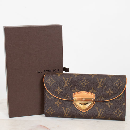 Louis Vuitton monogram wallet in brown coated canvas with gold-tone hardware, shown next to its brown presentation box on a light marble surface against a white background.