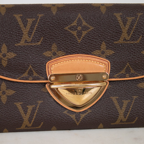Louis Vuitton monogram canvas clutch with a tan leather strap and a gold-tone metal clasp on a light marble surface.