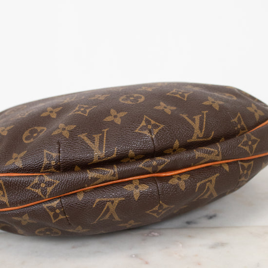 A Louis Vuitton monogram canvas pouch or small bag resting on a light marble surface against a white background.