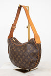 A Louis Vuitton monogram canvas shoulder bag with tan leather trim and strap, displayed on a gold-colored metal stand against a white background.