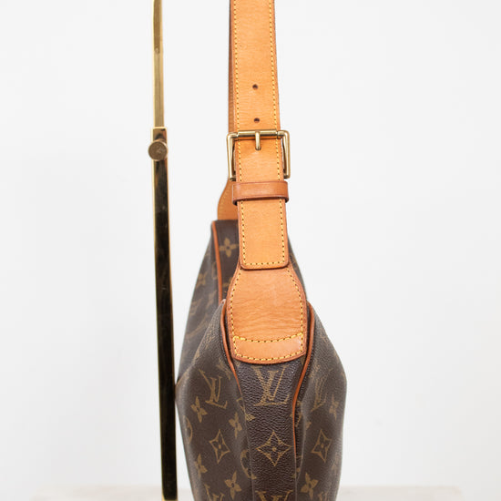 A Louis Vuitton monogram shoulder bag in brown coated canvas with tan leather trim and strap, displayed on a gold metal stand against a white background.