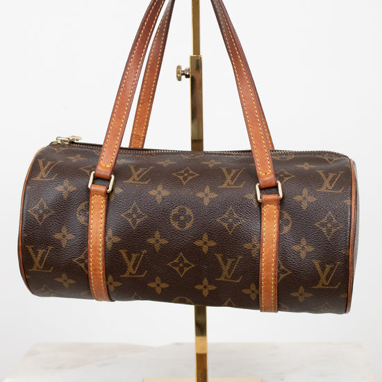 Louis Vuitton monogram canvas duffle bag with tan leather handles and trim, displayed on a gold stand against a white background.