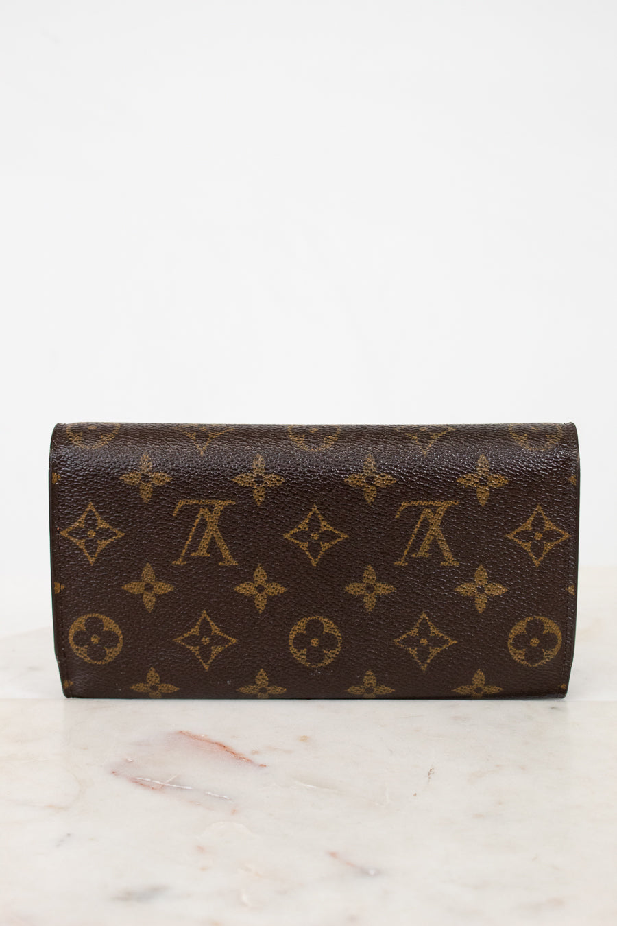 Louis Vuitton wallet with monogram pattern on a marble surface