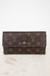 Louis Vuitton wallet with monogram pattern on a marble surface