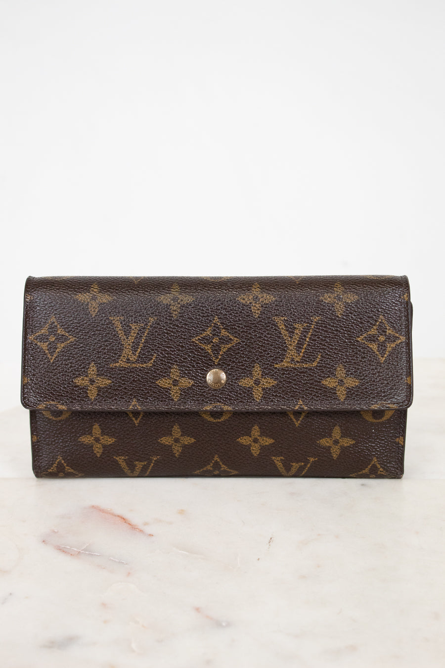 Louis Vuitton wallet with monogram pattern on a marble surface