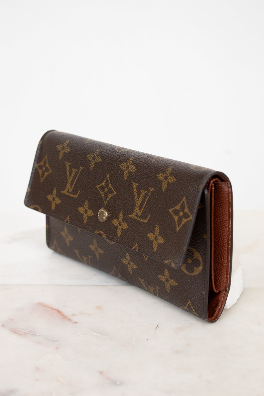 Louis Vuitton wallet with monogram pattern on a marble surface