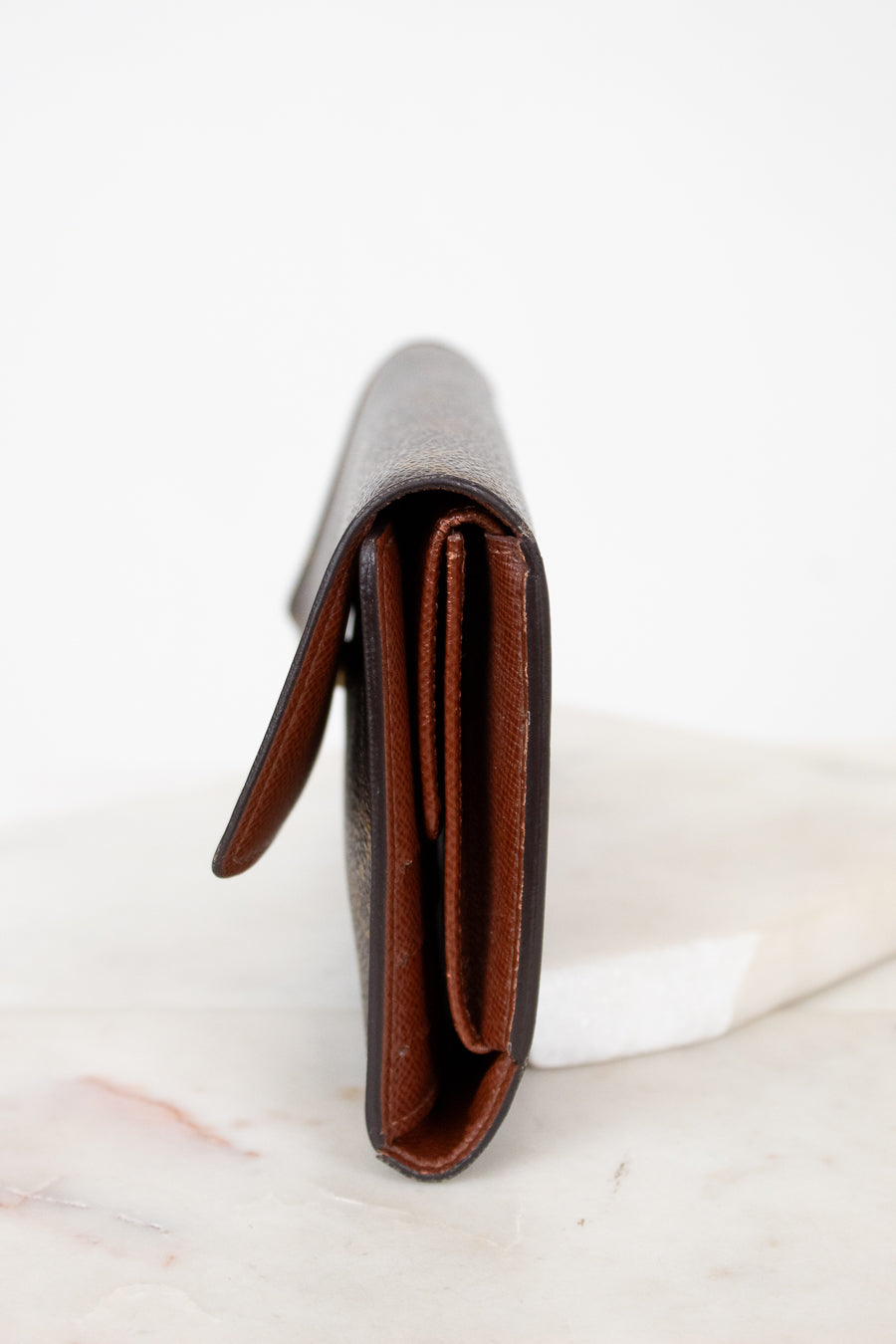 Close-up of side profile of a leather wallet on a white marble surface