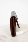 Side view of wallet with brown interior on a white marble surface