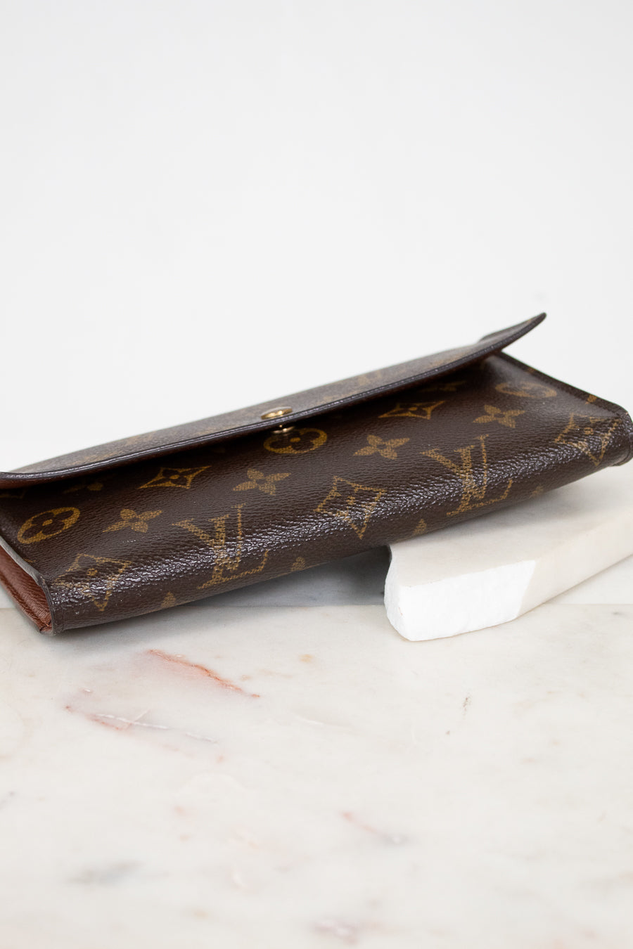 Brown Louis Vuitton wallet on a marble surface
