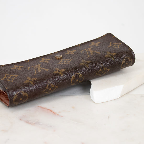 Brown wallet with monogram pattern on a marble surface