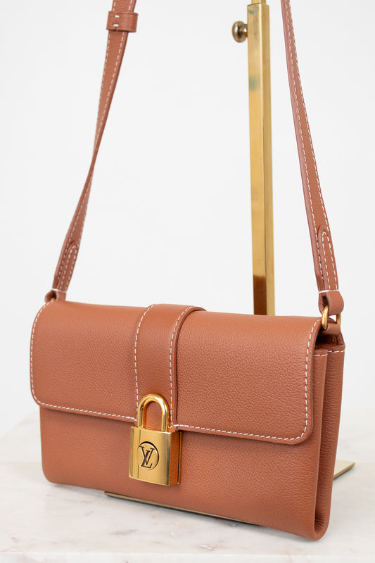 Brown leather handbag with gold lock on a white background